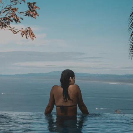 Vrouw in zwembad met uitzicht op zee