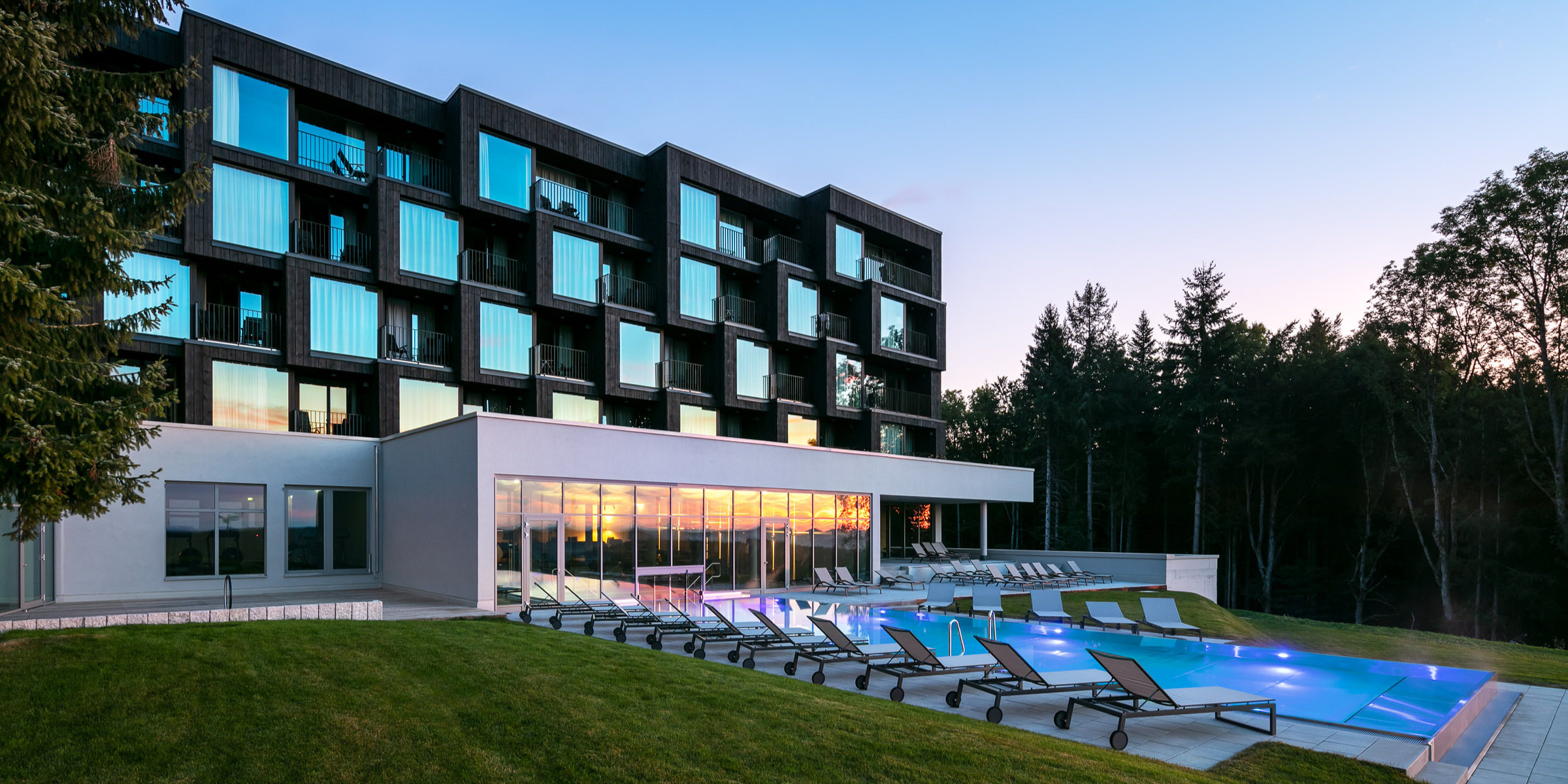 Buitenaanzicht-van-hotel-lauterbad-met-infinity-pool-en-ligstoelen-in-de-schwarzwald-bossen