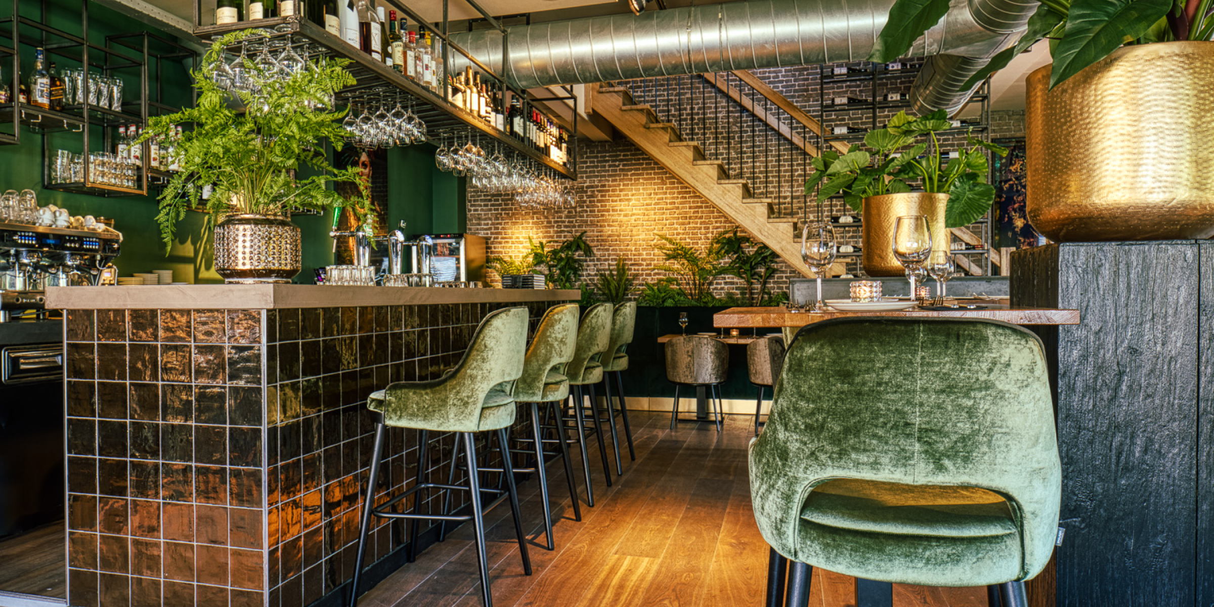 Interieur van ferro restaurant met groene fluwelen stoelen, moderne bar en warme sfeerverlichting.