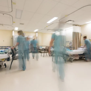 Zorgpersoneel loopt door ziekenhuisafdeling met patiëntenbedden in een frisse, hygiënische omgeving