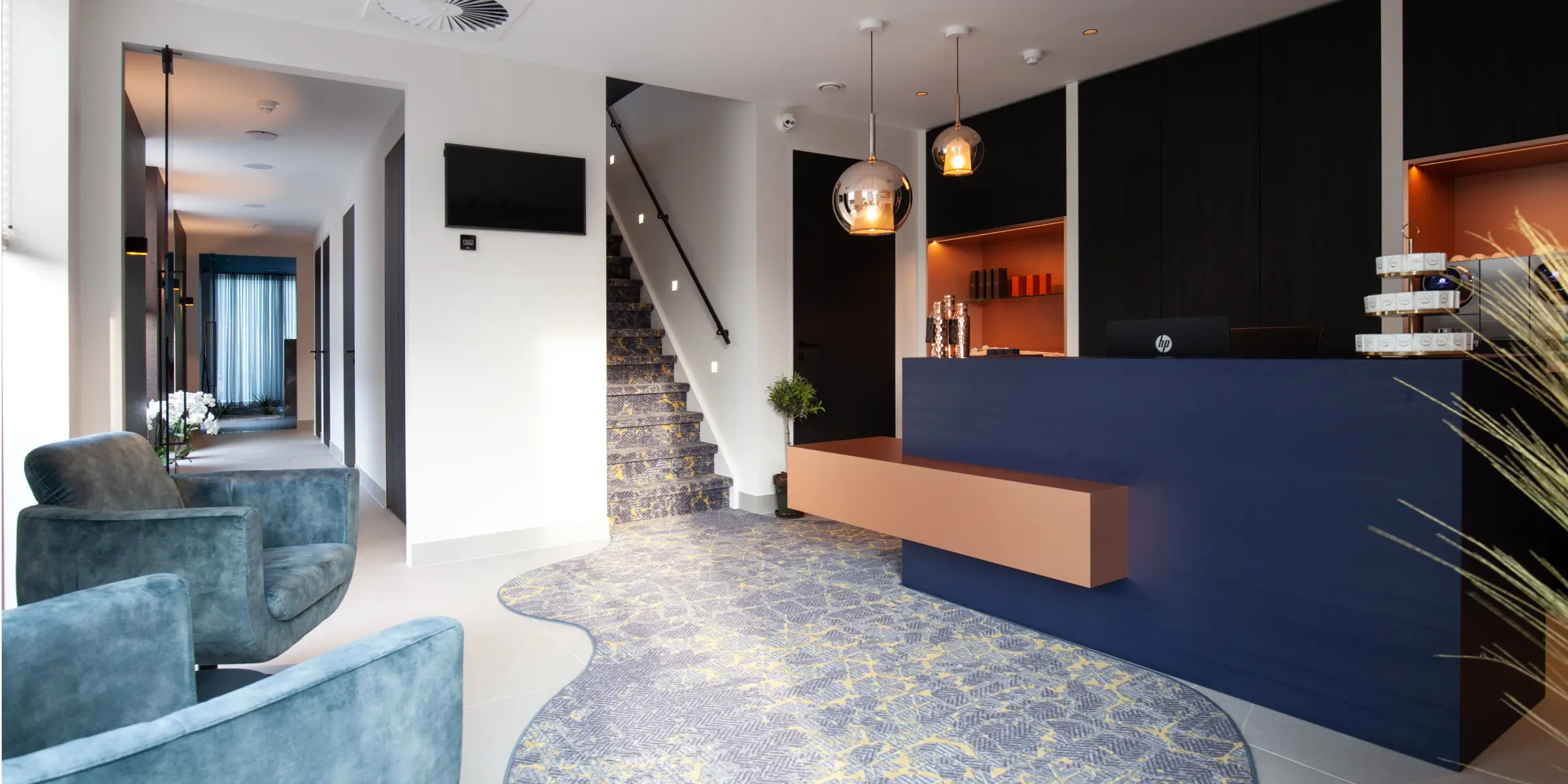 Stijlvolle receptie en lounge van een wellnesscentrum met moderne balie, comfortabele stoelen en trap, waar de geurbeleving van luxe geuren direct bij binnenkomst merkbaar is.