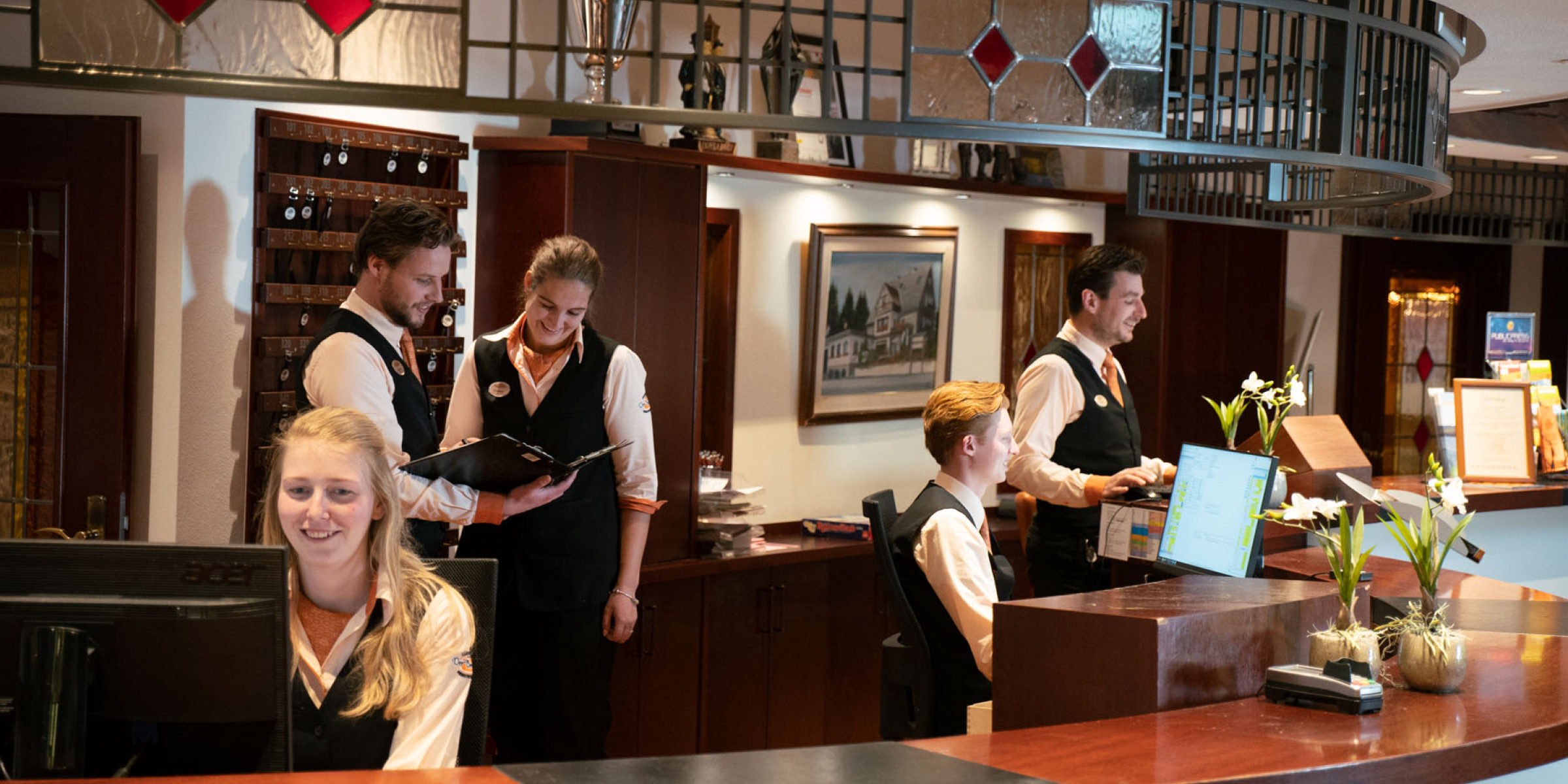 Geurmarketing-in-de-skihutte-van-hotel-der-brabander-skihutte-bar-personeel | allsens b. V. Teamleden in traditionele uniformen achter de houten bar van de skihütte van hotel der brabander; geurmarketing draagt bij aan de warme après‑ski‑sfeer.